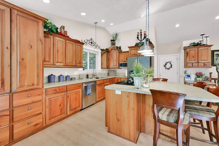 Kitchen featuring extensive wood cabinetry, light-colored countertops, stainless steel appliances, a center island with seating, and recessed lighting