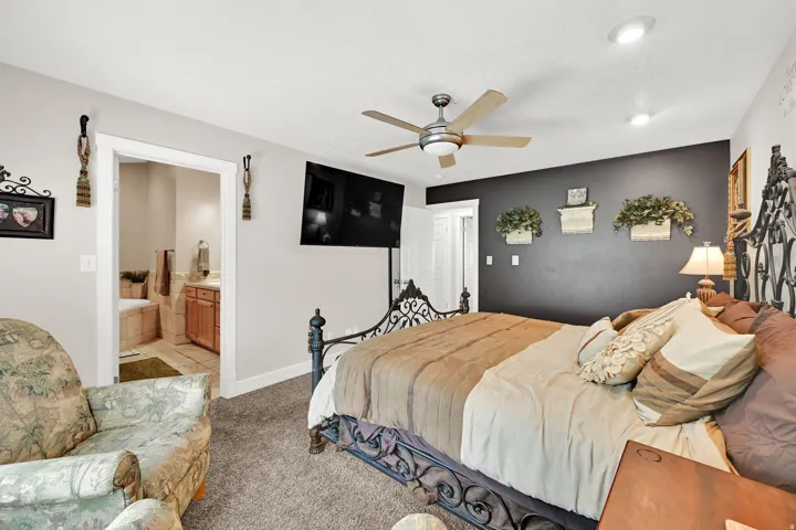 Carpeted bedroom featuring a ceiling fan, recessed lighting, and a dark accent wall