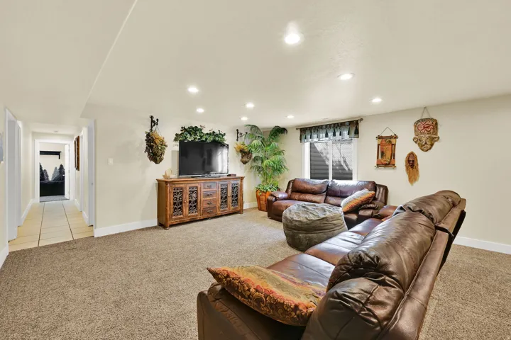 Carpeted living area with recessed lighting and a wood-finish media console