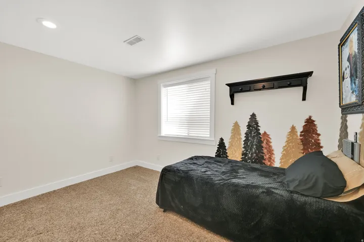 Carpeted room featuring a single window with blinds, recessed ceiling lighting, and a wall-mounted shelf