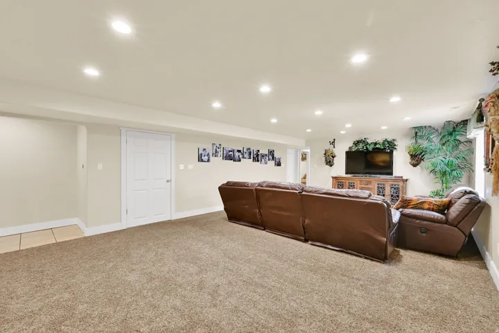 Spacious room featuring neutral carpeting, recessed lighting, white trim, and a paneled interior door