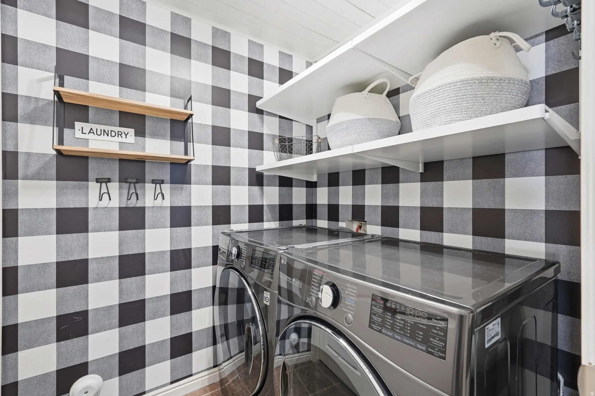 Laundry area featuring black and white buffalo check wall treatment, white ceiling with wood-finish planks, and durable wood-look flooring