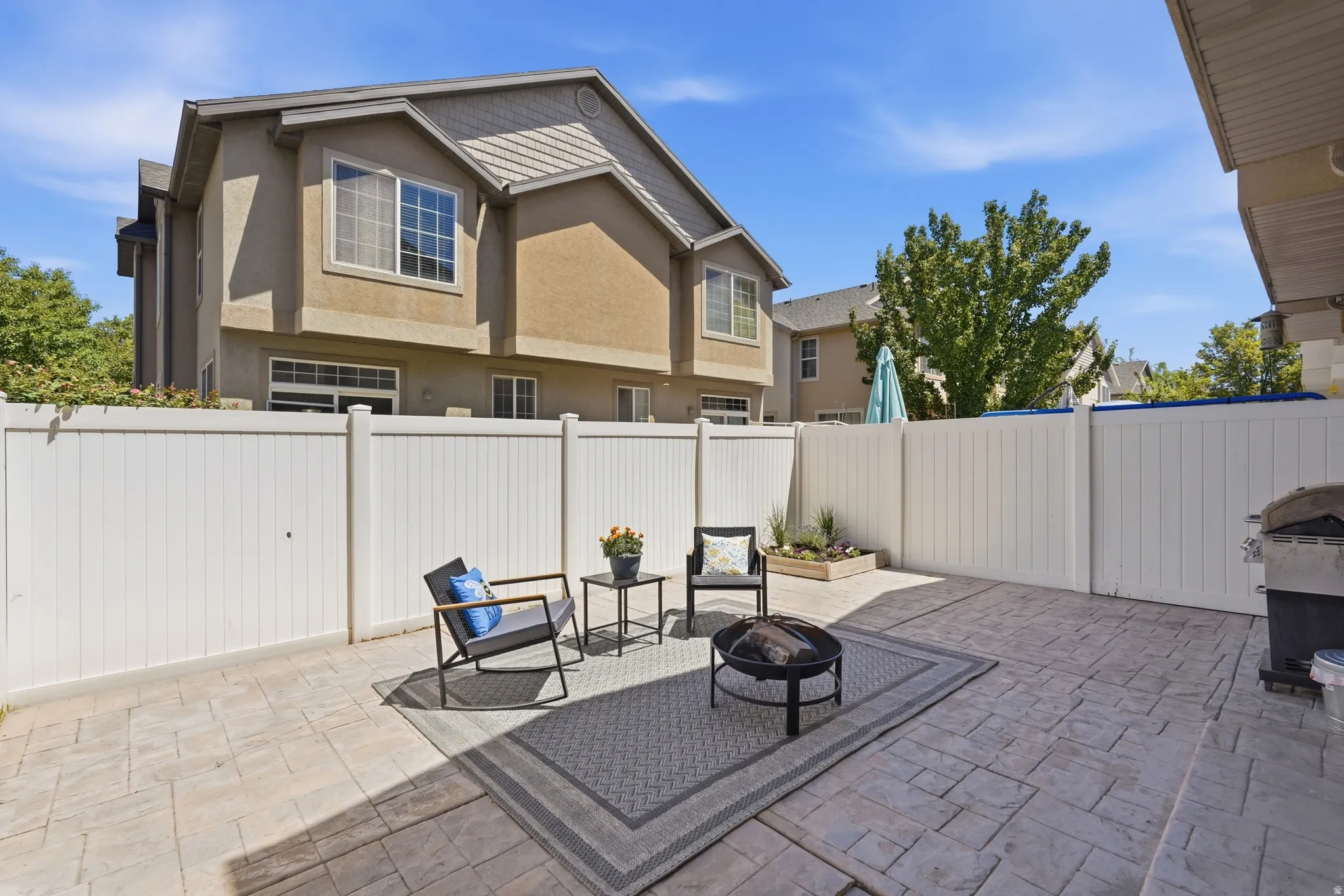 Patio area featuring stamped concrete flooring, white privacy fencing, and a built-in planter box