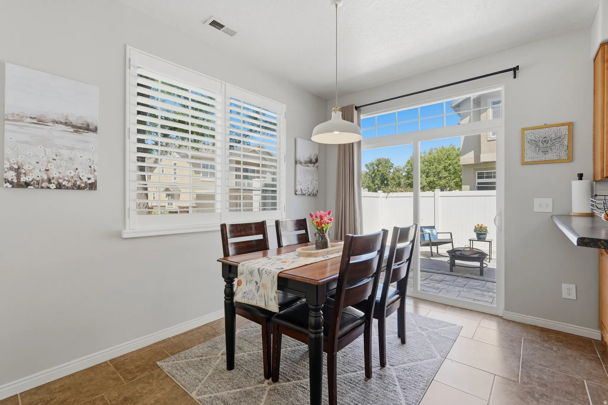 Dining area featuring white plantation shutters, a modern pendant light fixture, and tile flooring