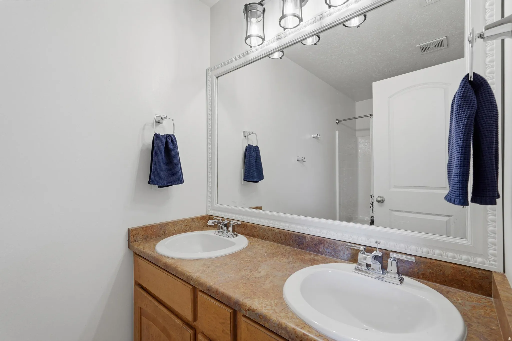 Dual vanity featuring laminate countertops, two undermount sinks with chrome fixtures, and wood-finish cabinetry