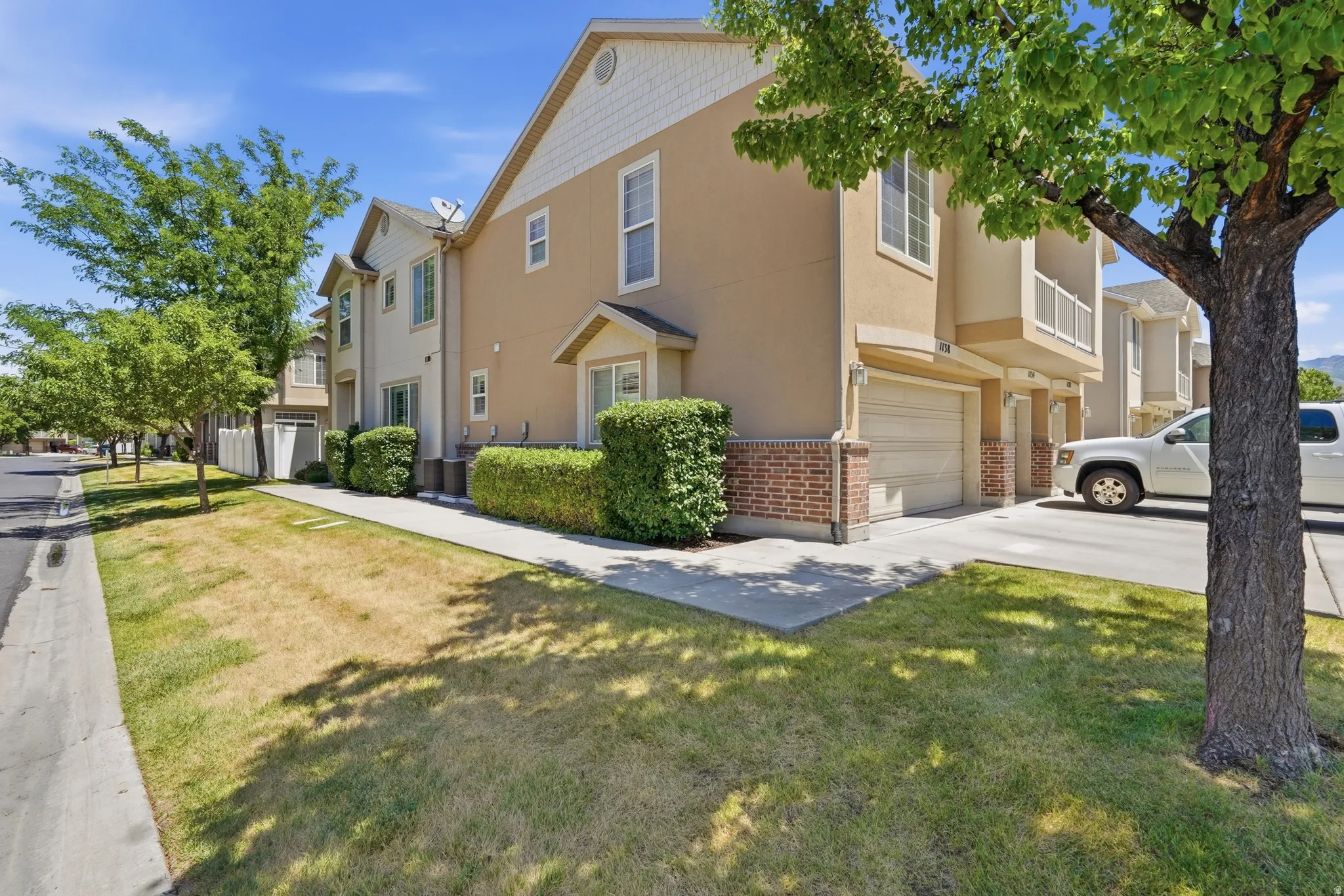 Two-story townhome featuring a neutral stucco exterior with brick accents and a two-car garage