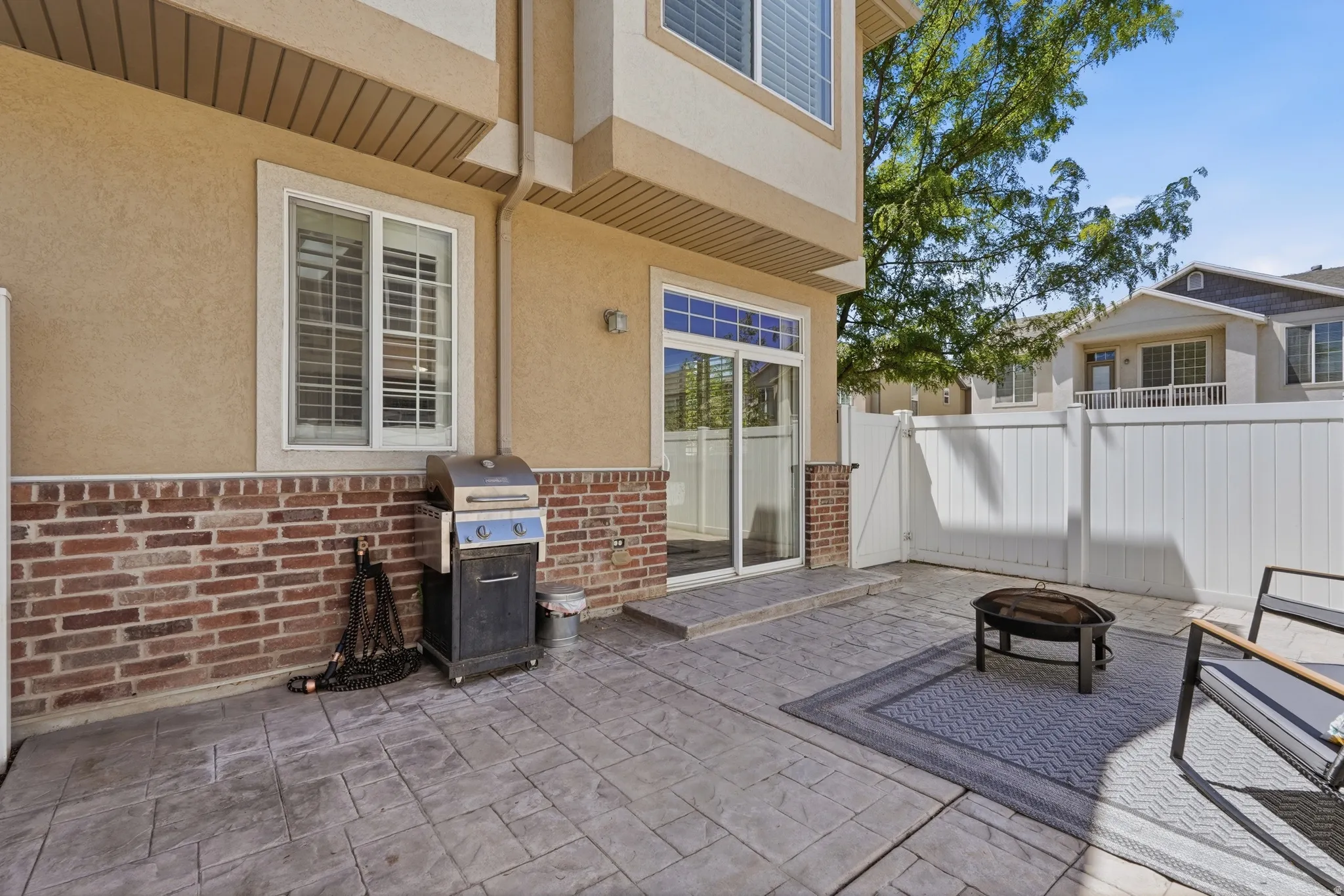Stamped concrete patio featuring a privacy fence and exterior brick detailing