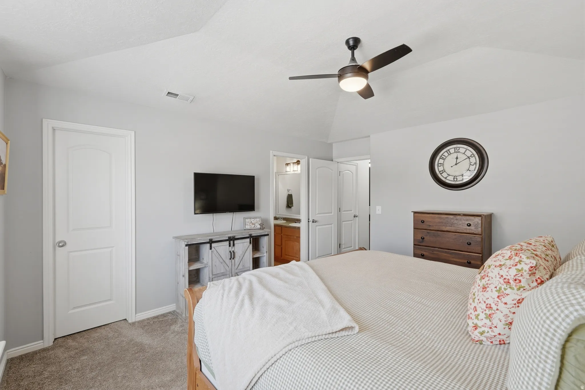 Vaulted ceiling with a ceiling fan, carpeted flooring, and a white panel door