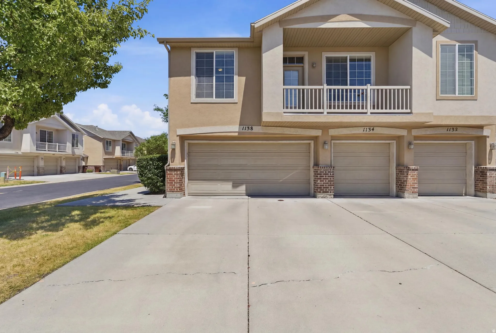 Multi-story property featuring a stucco exterior and multiple attached garages with brick accents