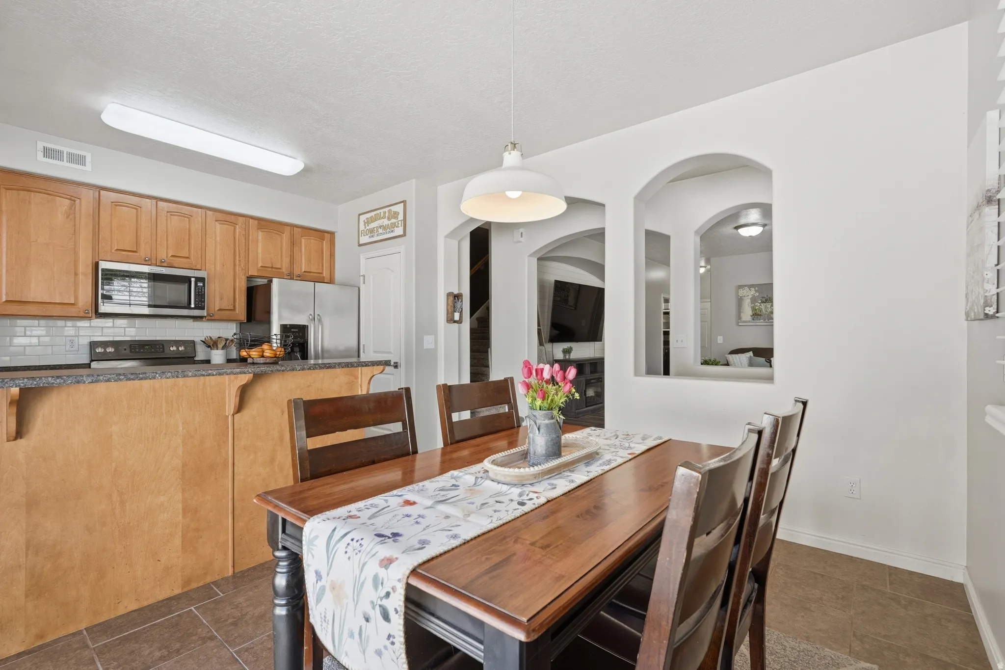 Dining area featuring a wood-finish table, a white pendant light fixture, and tile flooring