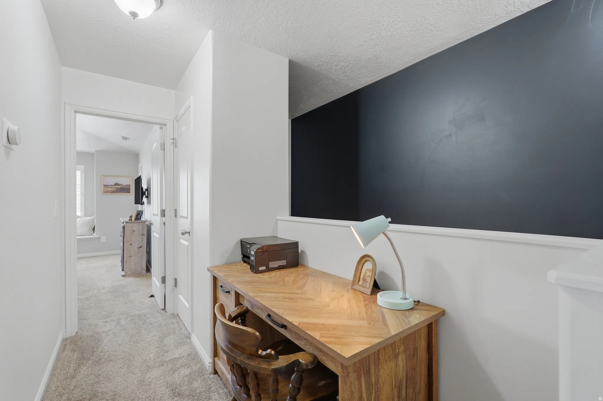 Dedicated desk area featuring a wood-finish desktop and dark accent wall