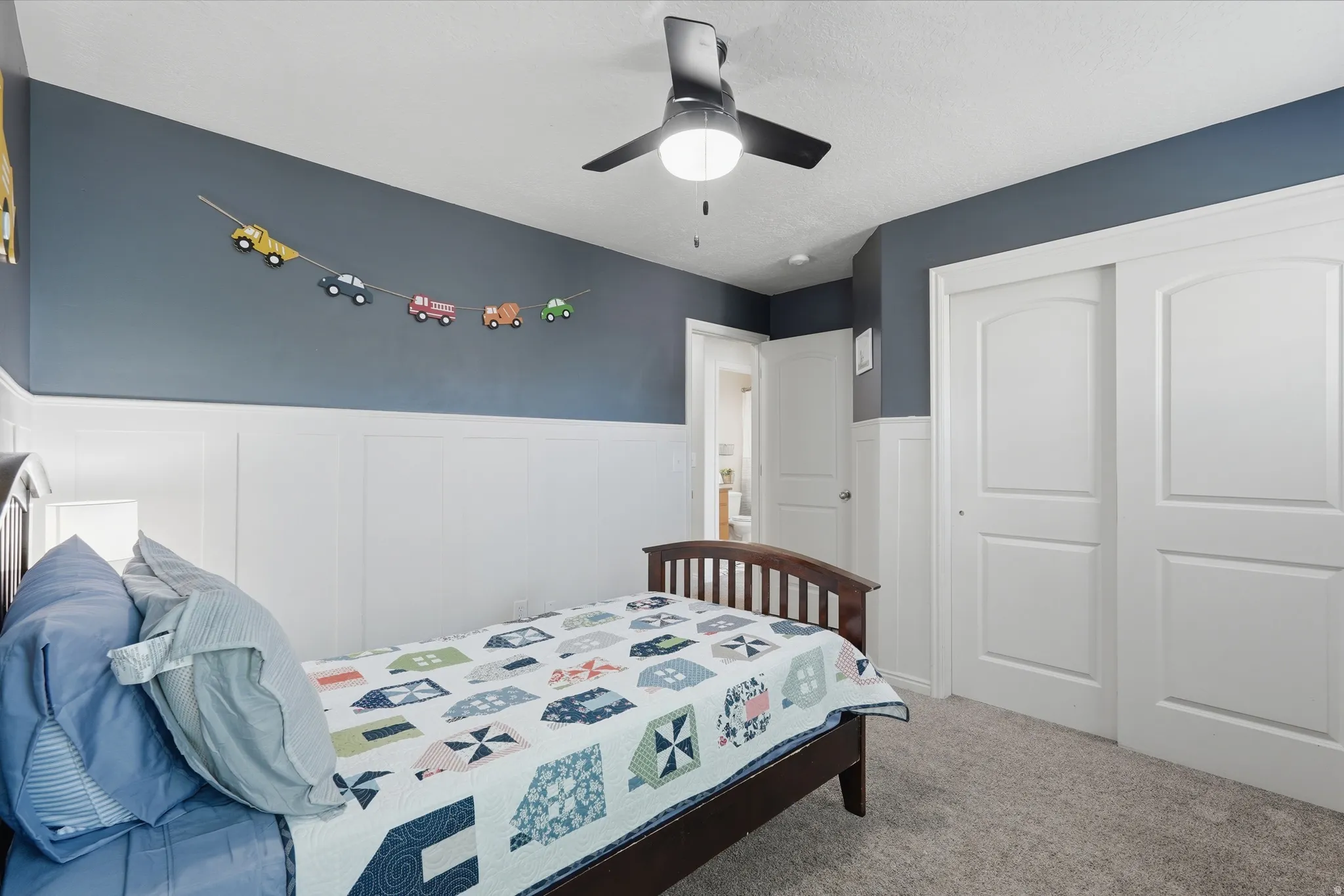 Bedroom featuring a vaulted ceiling with a ceiling fan, board and batten wall paneling, and sliding closet doors