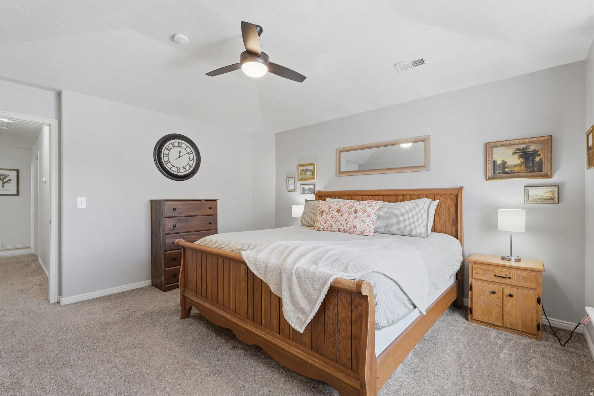 Carpeted bedroom featuring a vaulted ceiling and a ceiling fan with integrated lighting