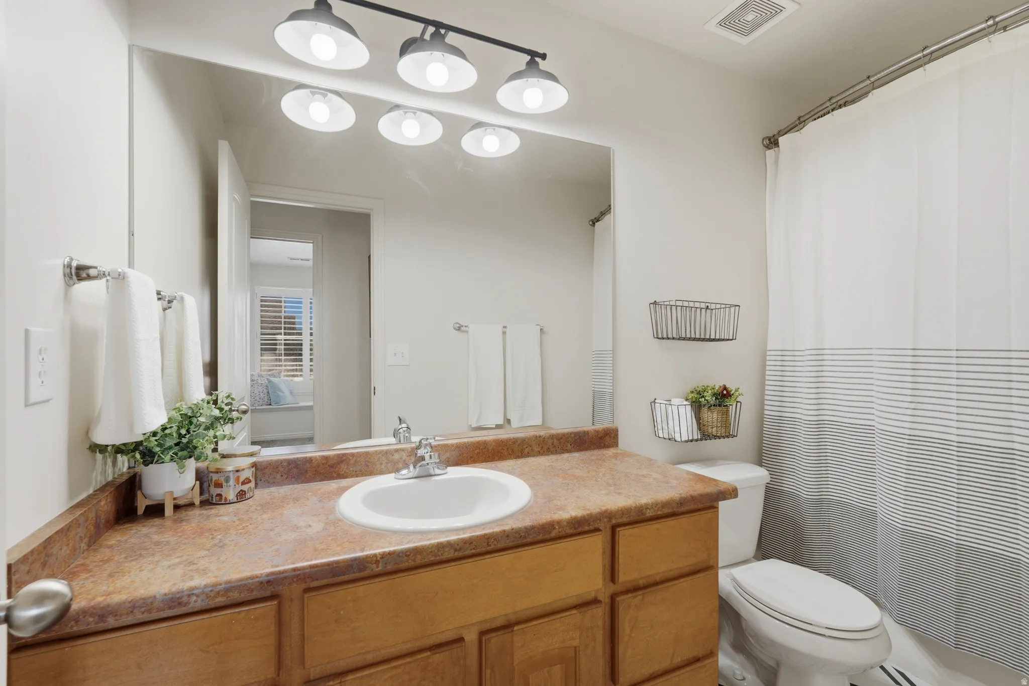 Bathroom featuring a single vanity with an integrated sink, a brown-hued countertop, and wood-finish cabinetry