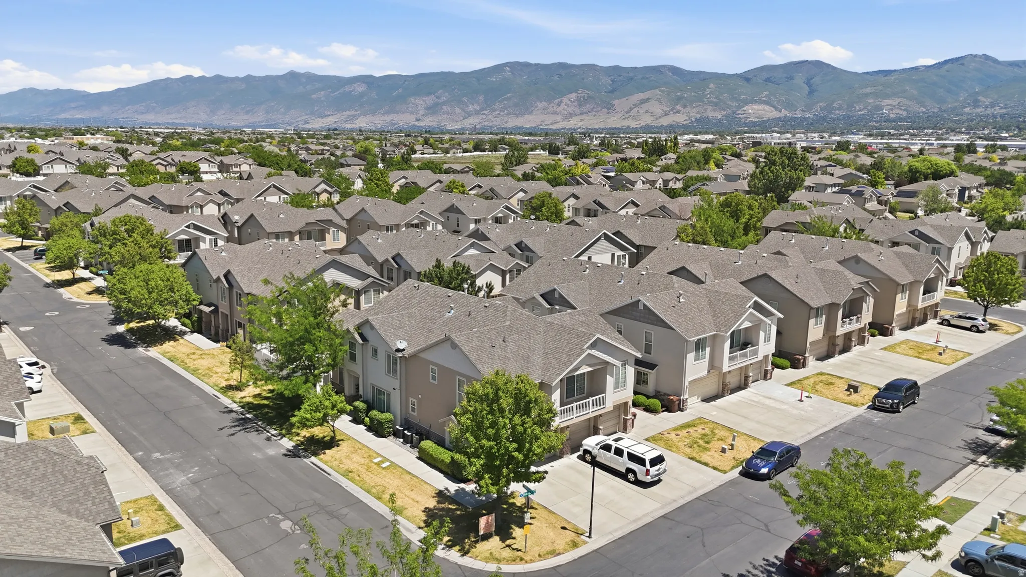 Aerial perspective showcasing multiple properties featuring light-colored siding, dark shingle roofs, integrated garages, and street-facing entrances