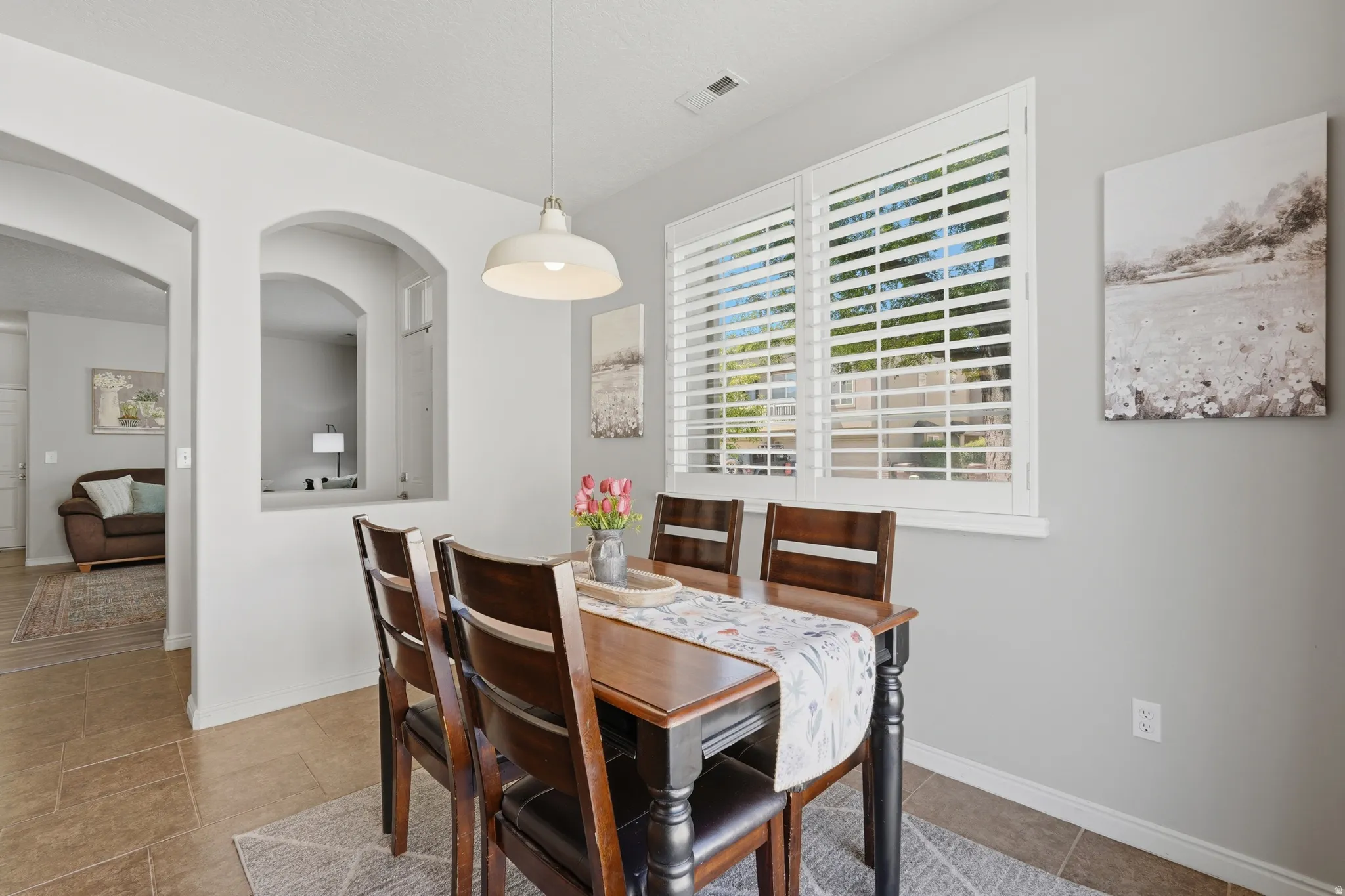 Dining area featuring a wood-finish table, four matching chairs, and a contemporary pendant light fixture