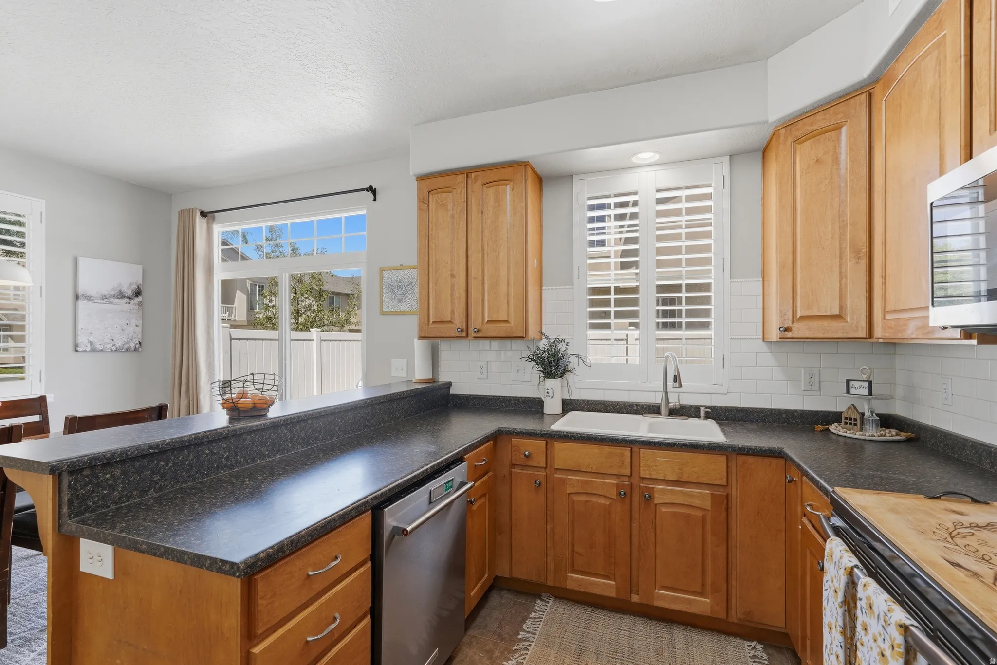 Kitchen featuring warm wood cabinetry, dark speckled countertops, and a white subway tile backsplash