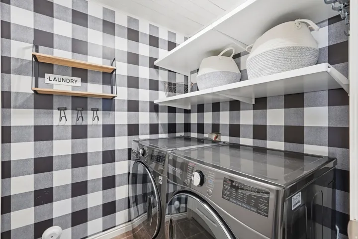 Laundry area featuring black and white buffalo check wall treatment, white ceiling with wood-finish planks, and durable wood-look flooring