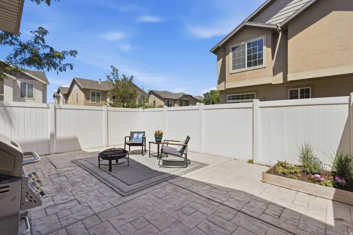Private patio space featuring stamped concrete, white vinyl fencing, and a built-in planter box