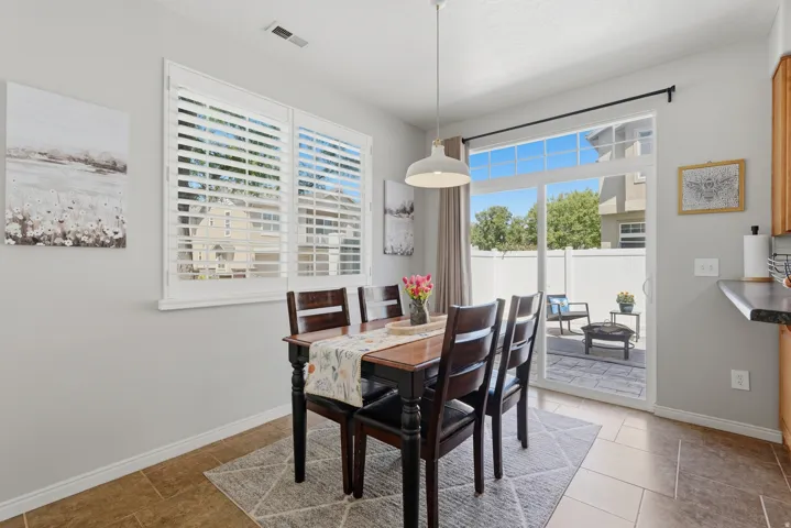 Dining area featuring white plantation shutters, a modern pendant light fixture, and tile flooring