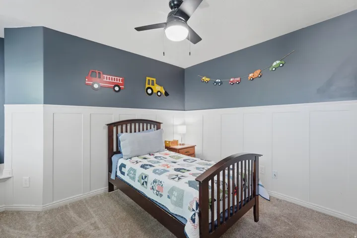 Bedroom featuring board and batten wainscoting, carpet flooring, a ceiling fan with integrated lighting, and a corner window ledge