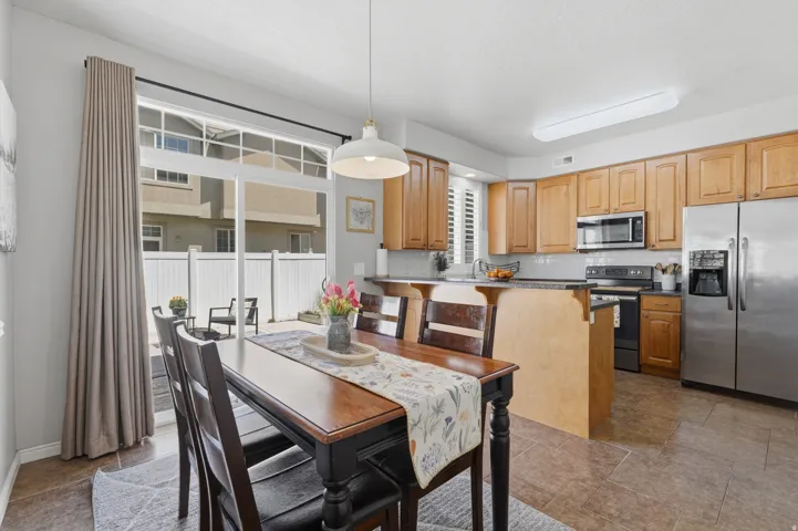 Kitchen and dining area featuring warm wood cabinetry, stainless steel appliances, and a breakfast bar with an overhang