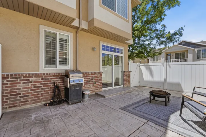 Stamped concrete patio featuring a privacy fence and exterior brick detailing