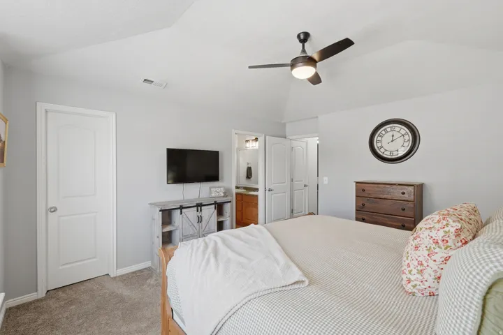 Vaulted ceiling with a ceiling fan, carpeted flooring, and a white panel door