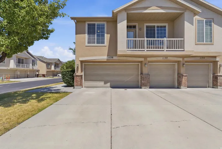 Multi-story property featuring a stucco exterior and multiple attached garages with brick accents