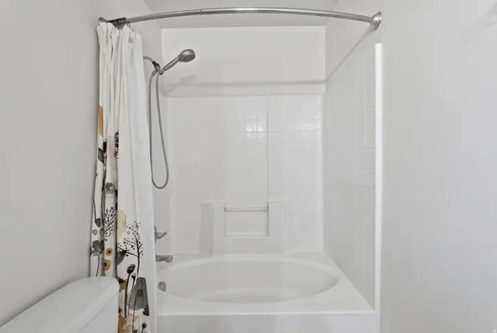 White tub and shower combination with a tiled surround and a built-in soap dish