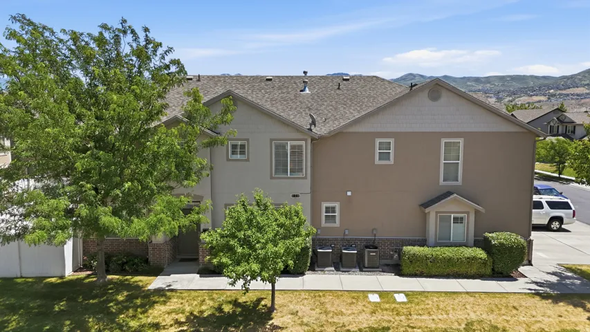 Multi-story property featuring a shingled roof, stucco siding, and a brick facade accent