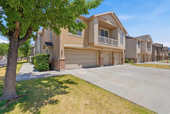 Stucco exterior with brick detailing, multiple attached garages, and a private balcony featuring a white railing