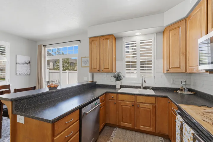 Kitchen featuring warm wood cabinetry, dark speckled countertops, and a white subway tile backsplash