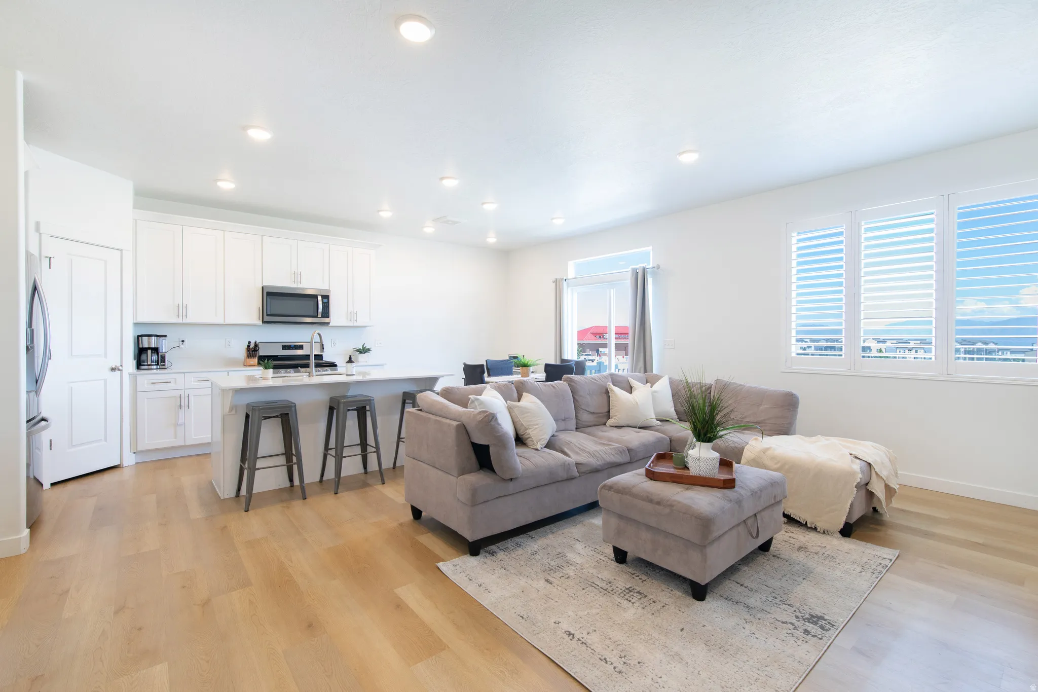Open-concept living space featuring light wood-finish flooring, recessed lighting, and white walls