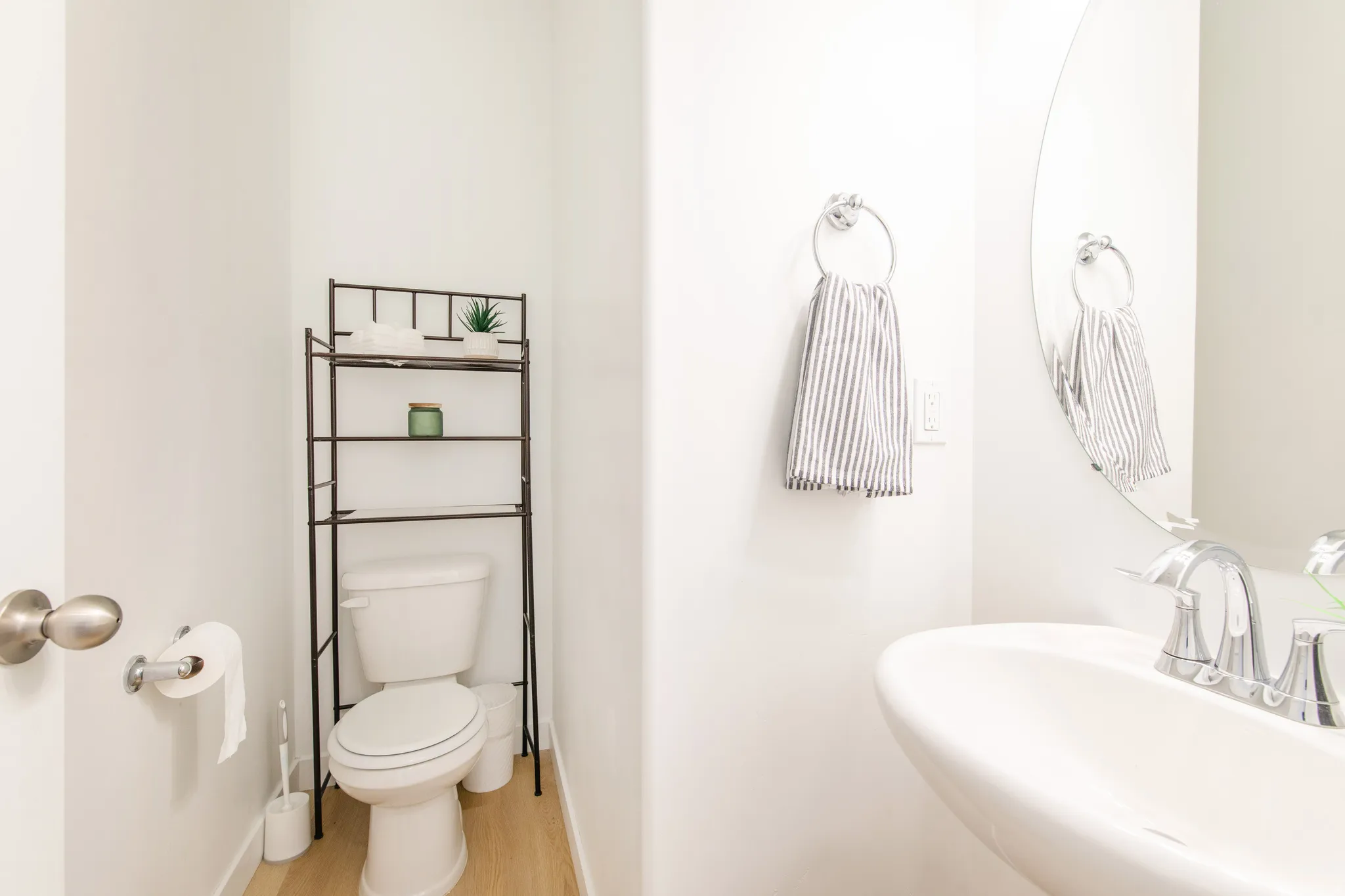 Pedestal sink with chrome fixtures and an oval mirror