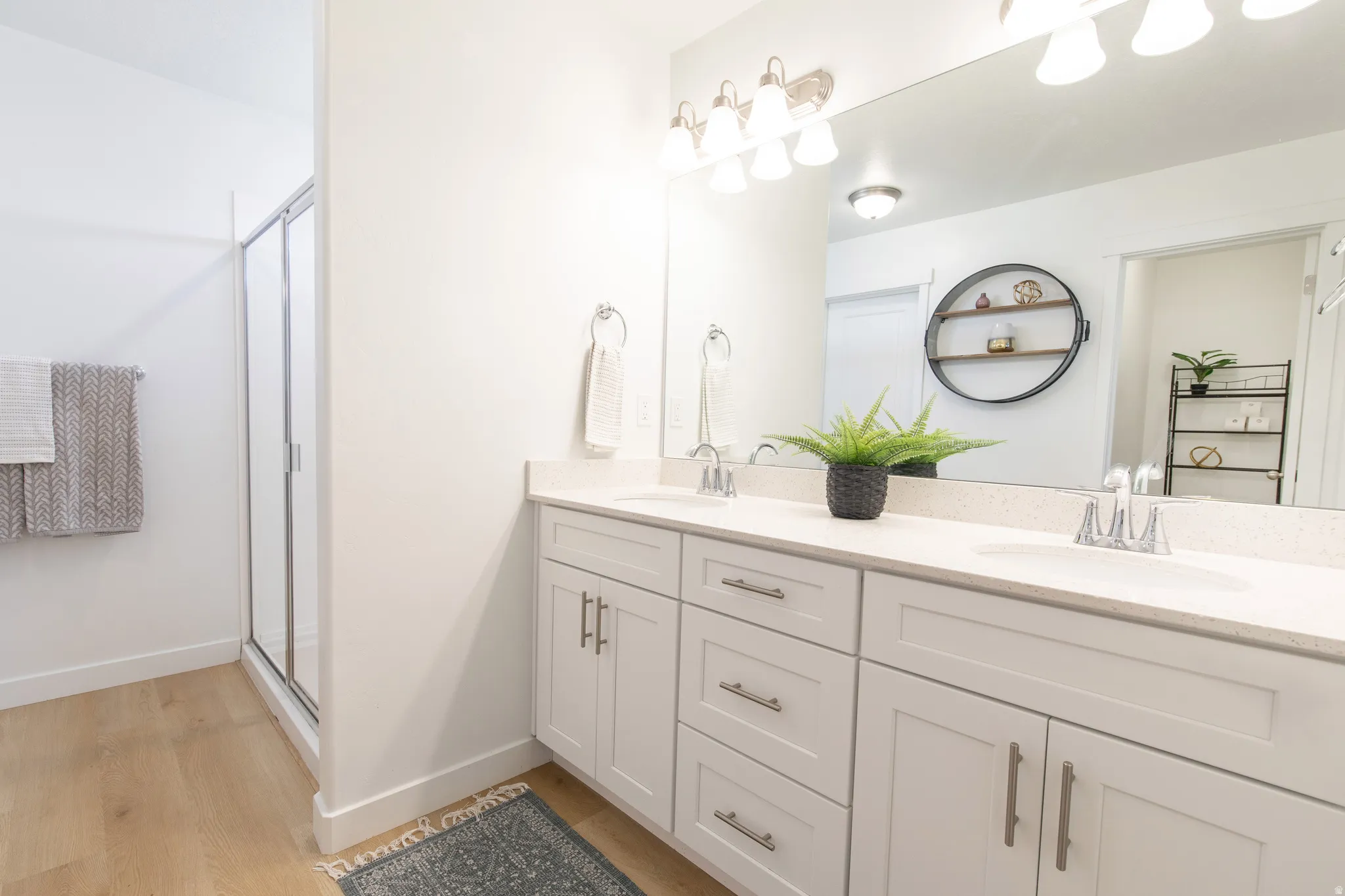 Double vanity featuring white shaker-style cabinetry, a light-colored countertop, and dual undermount sinks with chrome fixtures