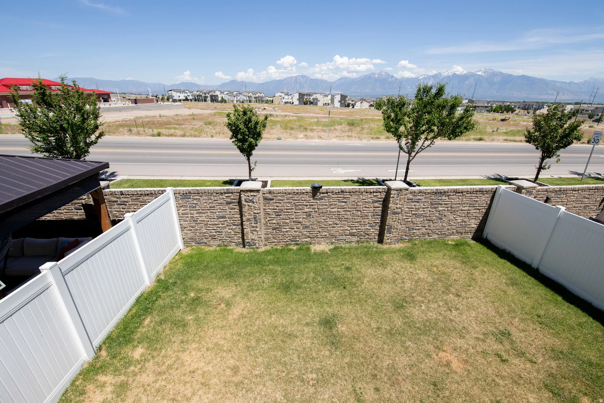 Backyard featuring a vinyl privacy fence, a stone retaining wall, and a covered patio structure