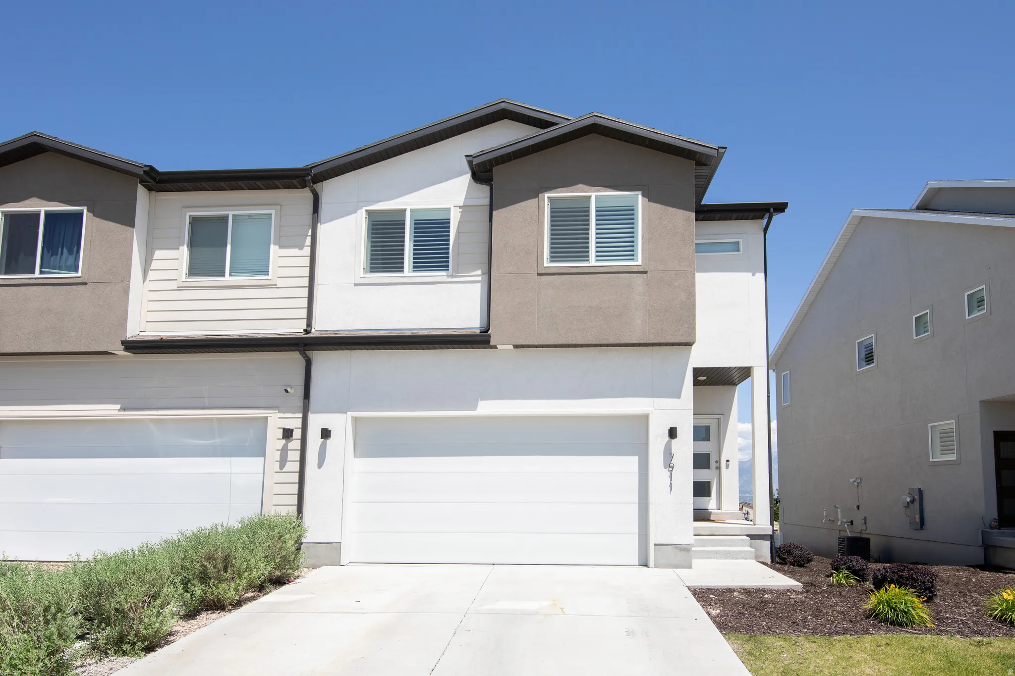 Contemporary multi-level townhome featuring a neutral-toned exterior with stucco and horizontal siding accents