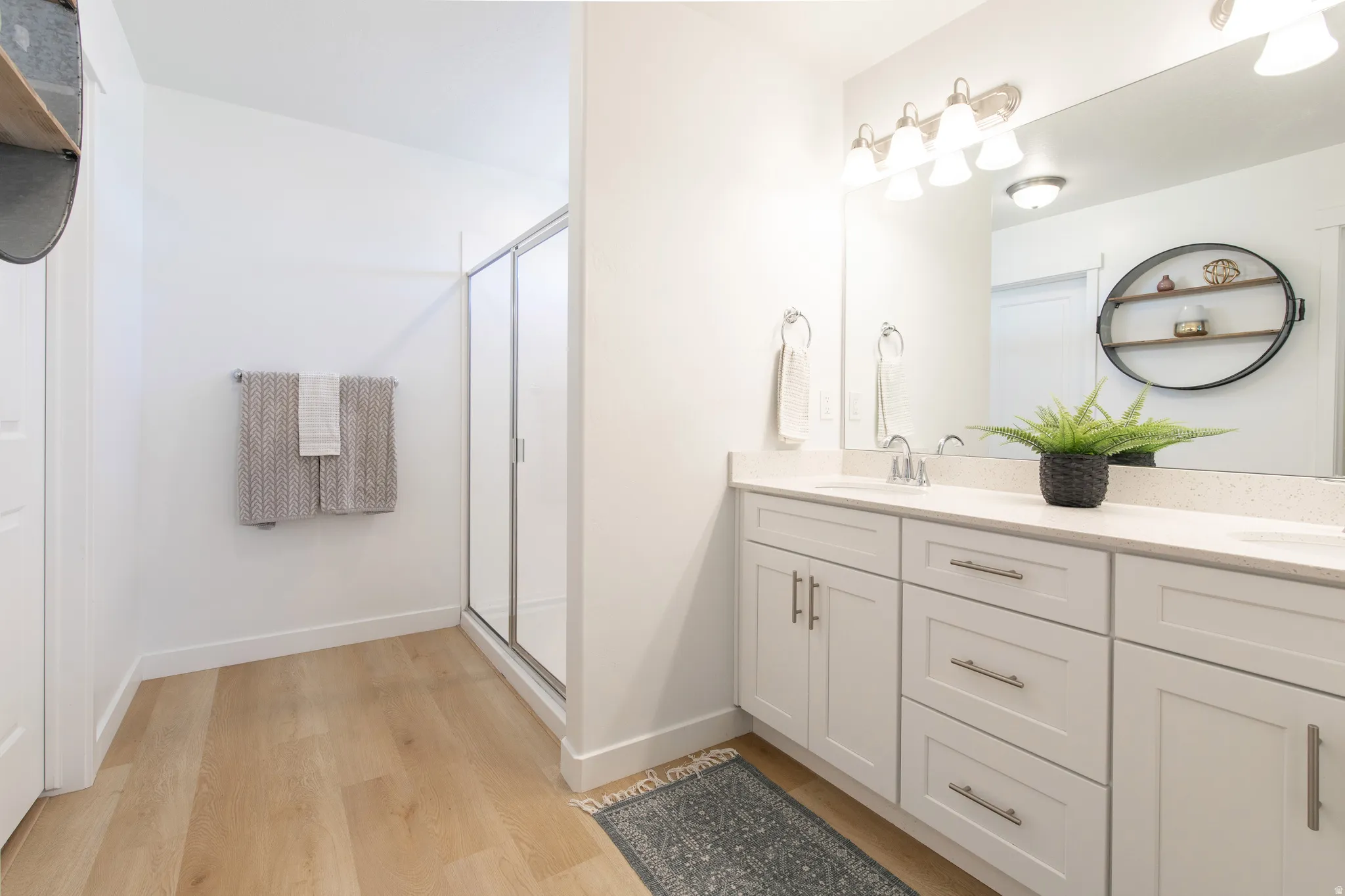 Bright bathroom featuring a dual vanity with white shaker-style cabinetry and a light-toned countertop