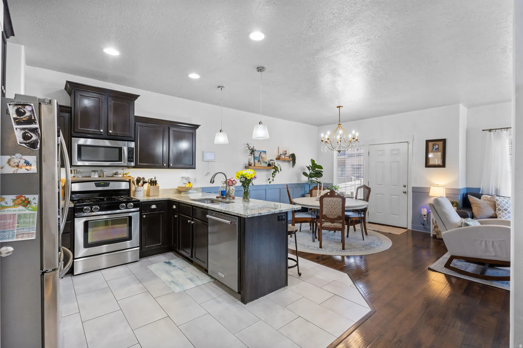 Kitchen featuring dark wood cabinetry, stainless steel appliances, and light-toned tile flooring