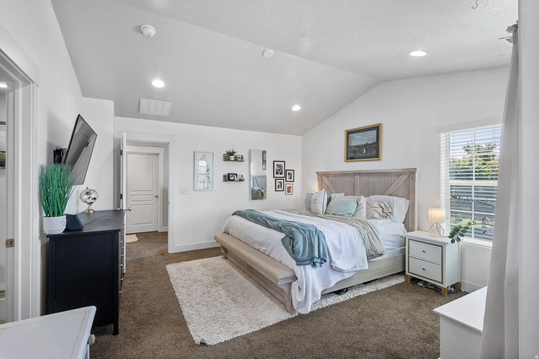 Vaulted ceilings enhance this bedroom featuring recessed lighting, a window with horizontal blinds, and carpeted flooring