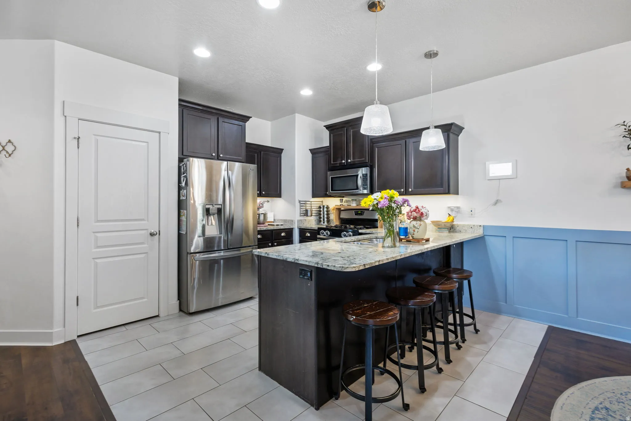 Kitchen featuring dark wood cabinetry, stainless steel appliances, and a central island with a light-colored countertop