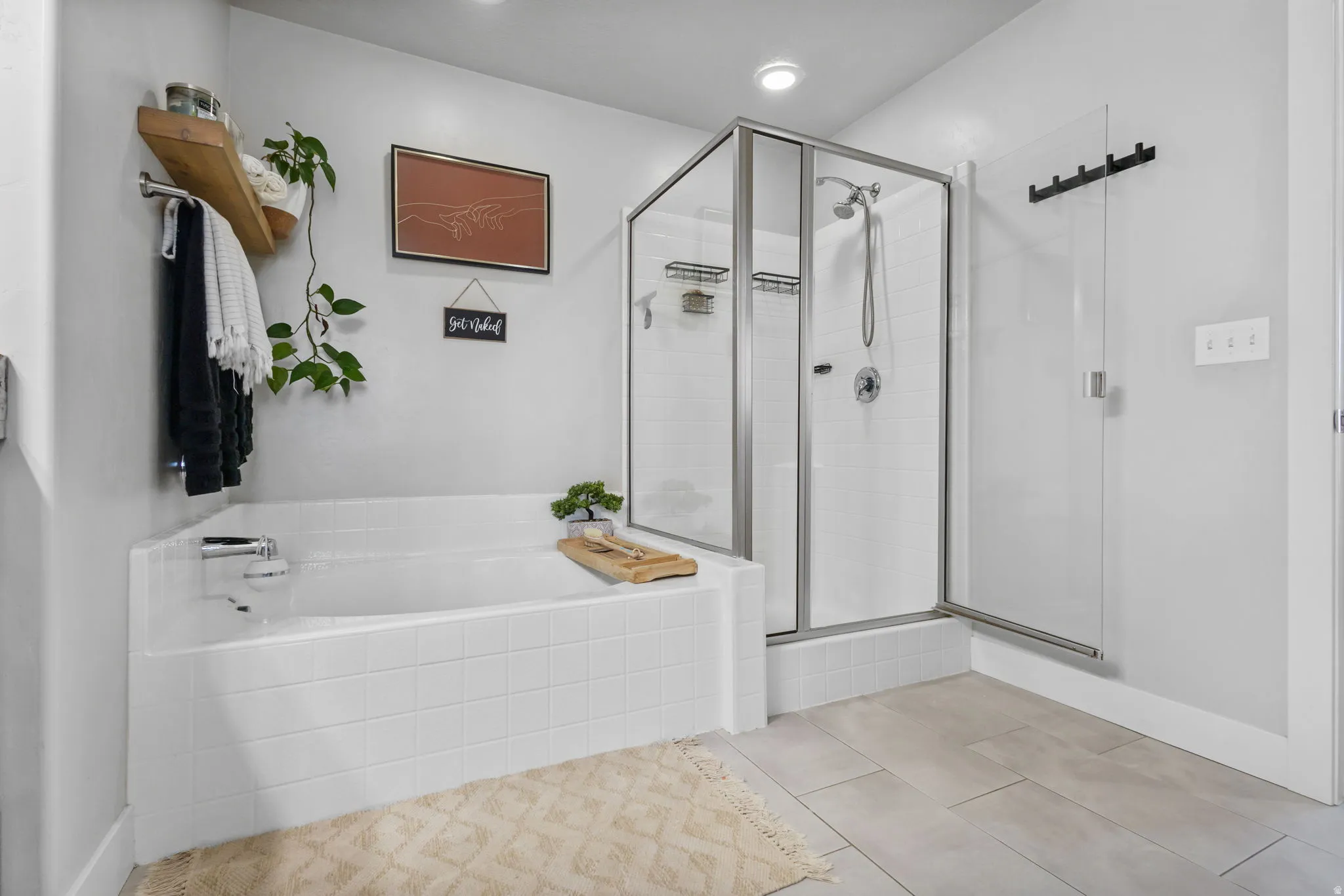 Tiled soaking tub and separate glass-enclosed shower featuring a handheld showerhead