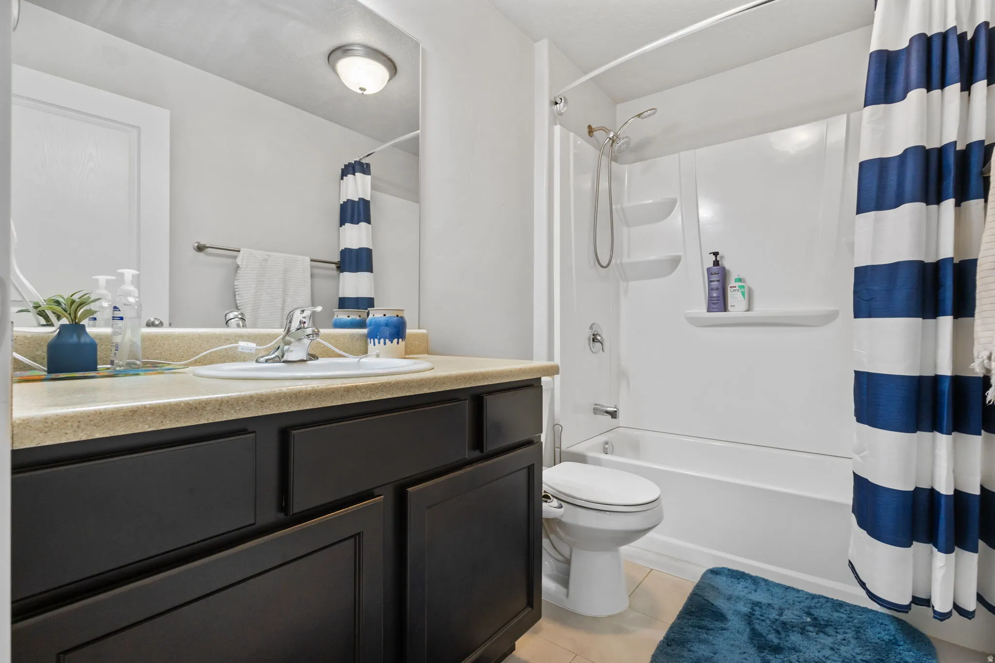 Bathroom featuring a built-in vanity with dark wood-finish cabinetry, a white porcelain sink, and a light-toned countertop