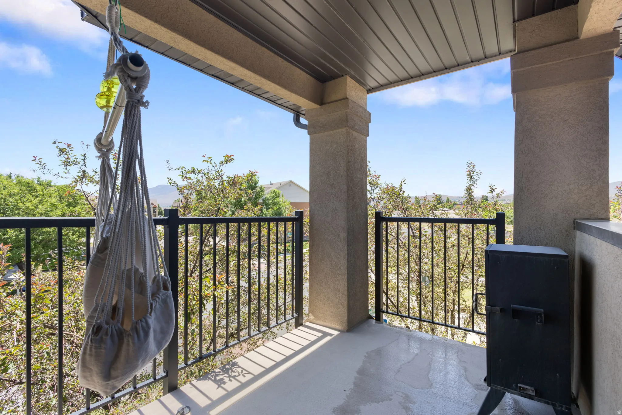 Covered balcony featuring concrete flooring and a black metal railing