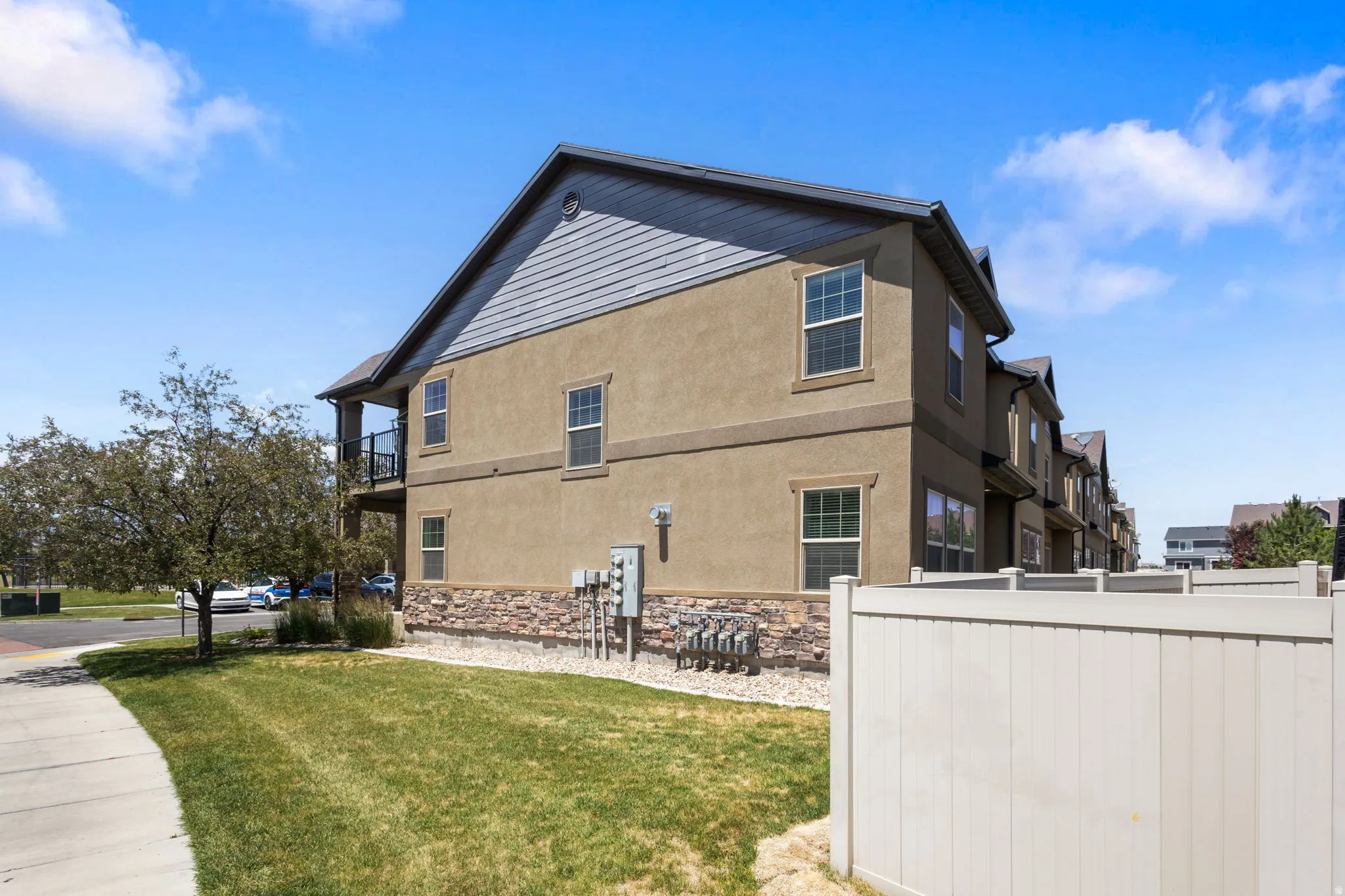Multi-level residence featuring stucco and horizontal siding, stone facade detailing, and a black railing balcony