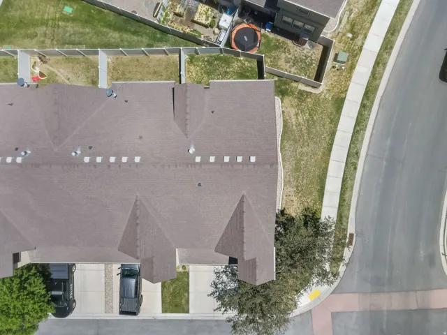 Townhome property featuring a brown shingle roof, paved driveway, and dedicated carport