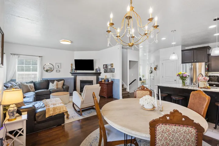 Open-concept living space featuring wood-finish flooring, a fireplace with a tiled surround and dark wood mantel, and a kitchen island with a light-toned countertop