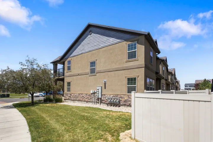 Multi-level residence featuring stucco and horizontal siding, stone facade detailing, and a black railing balcony