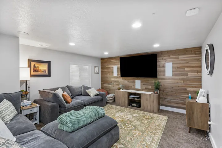 Entertainment room featuring a wood-panel accent wall, recessed lighting, and carpet flooring